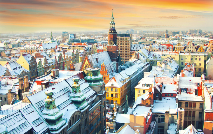 Stadt im Winter mit schneebedeckten Gebäuden und malerischem Himmel bei Sonnenuntergang.