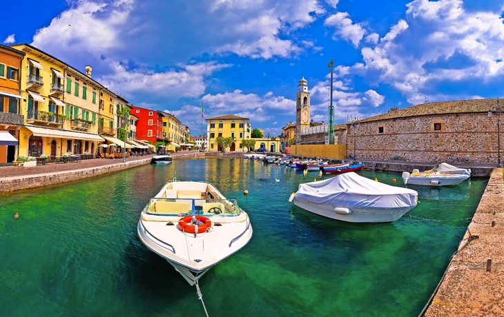 Bunte Häuser und Boote im Hafen einer historischen italienischen Stadt.