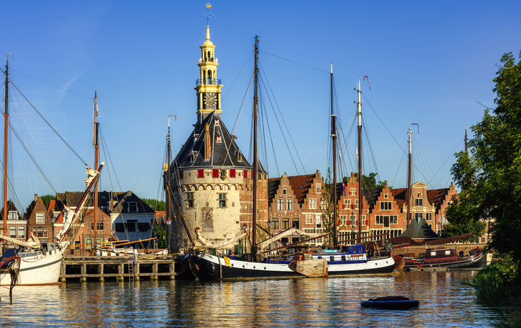 Hafenansicht mit historischen Gebäuden und Segelbooten bei sonnigem Wetter.
