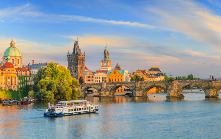 Panoramablick auf Prag mit Karlsbrücke und Moldau im Vordergrund.